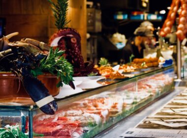 Una vetrina di un mercatino di Natale ricca di cibi freschi da acquistare come salumi, pesci, crostacei