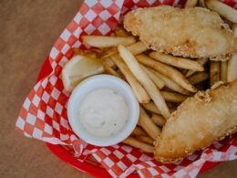 Una porzione di fish & chips, pesce fritto e patatine, servite in un cesto rosso da fast food