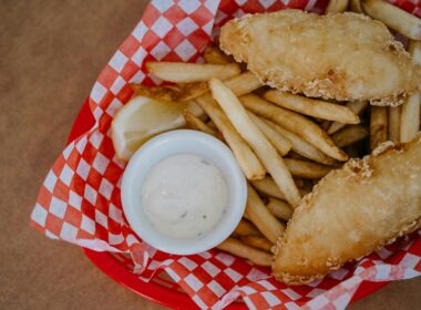 Una porzione di fish & chips, pesce fritto e patatine, servite in un cesto rosso da fast food