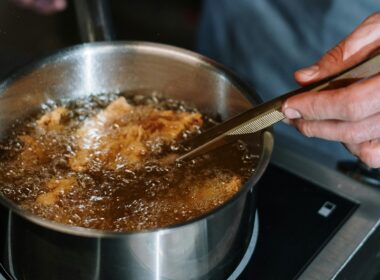 Una pentola piena di olio bollente e del cibo che sta friggendo formando una serie di bollicine in superficie