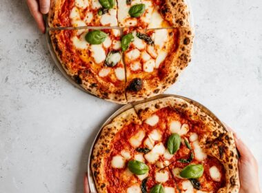 Due pizze napoletane con salsa di pomodoro, mozzarella e basilico su un piano da lavoro in marmo bianco