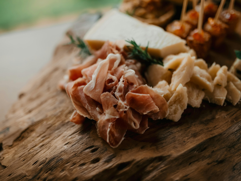 un tagliere di legno su cui sono stati poggiati vari salumi, tra quelli italiani più famosi, a fette o tocchetti