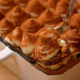 È visibile una parte di una pirofila che contiene un tiramisù. Si intravede la crema al mascarpone e la spolverata di cacao amaro in superficie