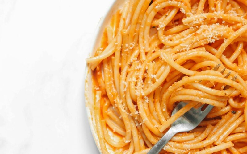 L'immagine presenta un piatto pieno di pastasciutta, ovvero sdegli spaghetti conditi con salsa di pomodo e parmigiano grattugiato