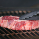 Una fetta di carne poggiata su una griglia accesa