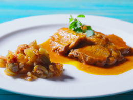 un piatto di caponata siciliana su un tavolo celeste