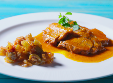 un piatto di caponata siciliana su un tavolo celeste