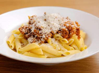 un piatto di pasta al ragù condito con del formaggio grattugiato