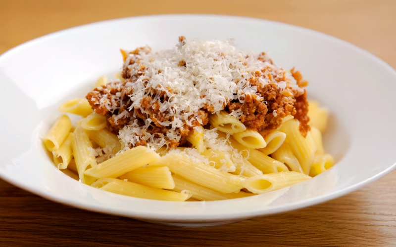 un piatto di pasta al ragù condito con del formaggio grattugiato