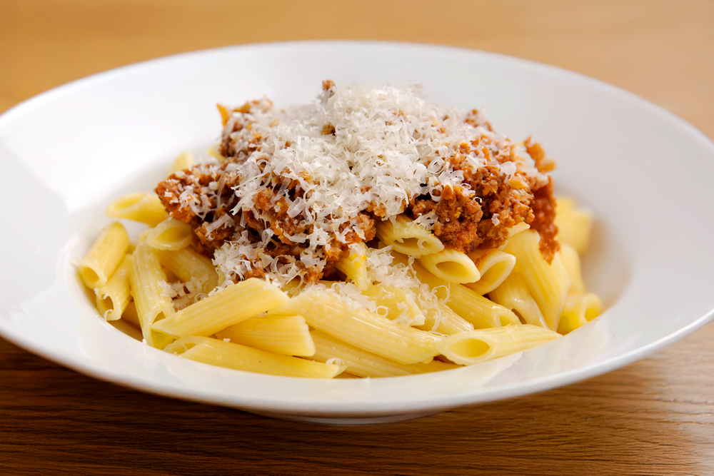 un piatto di pasta al ragù condito con del formaggio grattugiato
