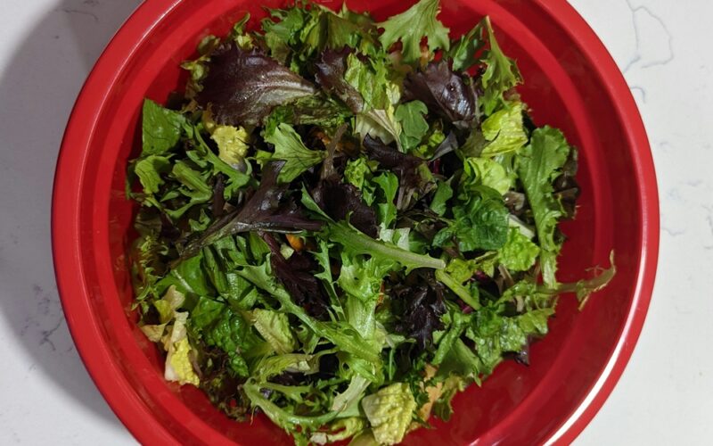 una ciotola rossa piena di foglie di insalata