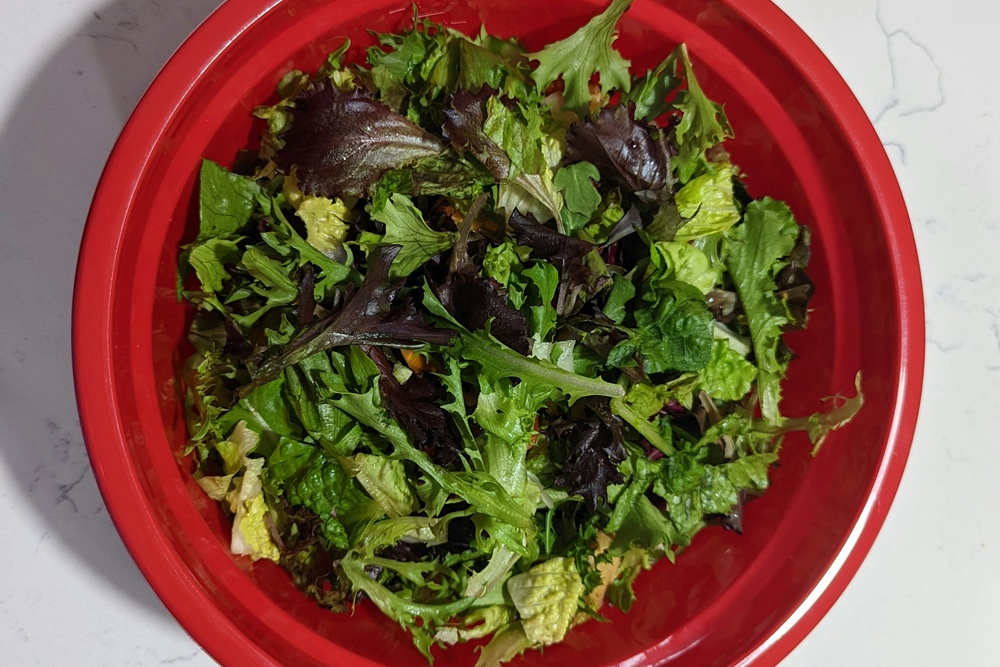 una ciotola rossa piena di foglie di insalata