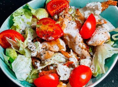 una bowl di caesar salad con pomodori, insalata, pollo e salsa caesar