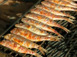 una griglia su cui sta cuocendo del pesce, precisamente delle sardine