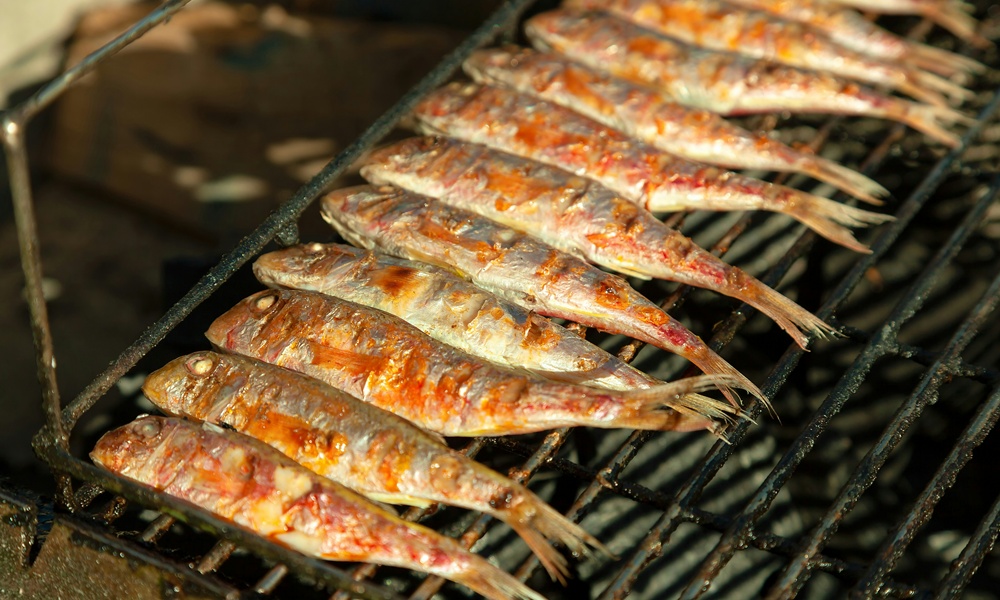 una griglia su cui sta cuocendo del pesce, precisamente delle sardine