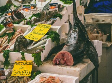 un frame di un mercato del pesce con in vendita un pezzo di pesce spada di cui si intravede l'interno e il prezzo