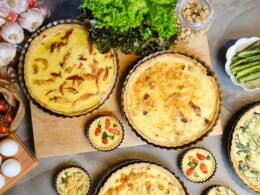 una tavola imbanita con diverse quiche lorraine di diversi gusti e dimensioni