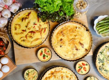 una tavola imbanita con diverse quiche lorraine di diversi gusti e dimensioni