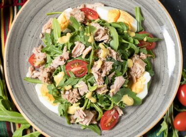 un piatto in cui è contenuta un'insalata a base di spinacino, tonno in scatola, uova e pomodorini