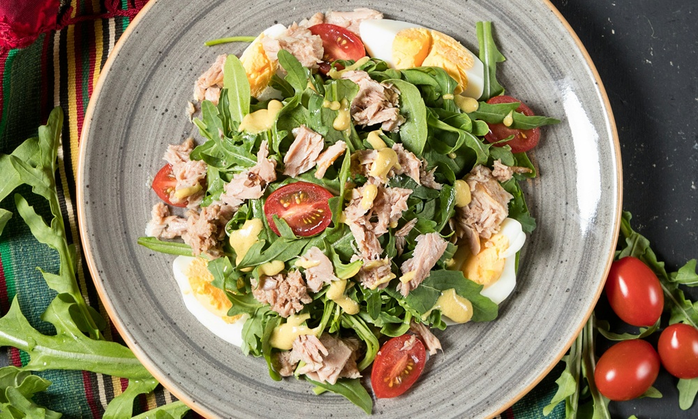 un piatto in cui è contenuta un'insalata a base di spinacino, tonno in scatola, uova e pomodorini