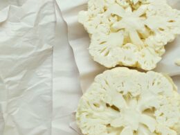 un cavolfiore bianco crudo tagliato a mo di bistecca posato su un panno bianco e pronto da mangiare crudo
