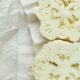 un cavolfiore bianco crudo tagliato a mo di bistecca posato su un panno bianco e pronto da mangiare crudo