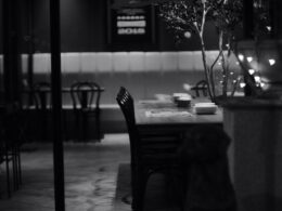 Una foto in bianco e nero in cui si intravede un tavolo di un ristorante per una cena da soli per uno