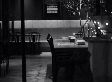 Una foto in bianco e nero in cui si intravede un tavolo di un ristorante per una cena da soli per uno