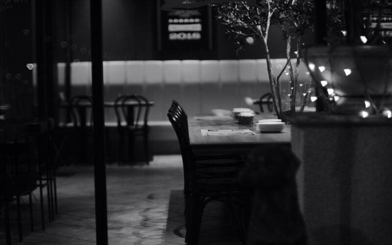 Una foto in bianco e nero in cui si intravede un tavolo di un ristorante per una cena da soli per uno