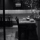 Una foto in bianco e nero in cui si intravede un tavolo di un ristorante per una cena da soli per uno