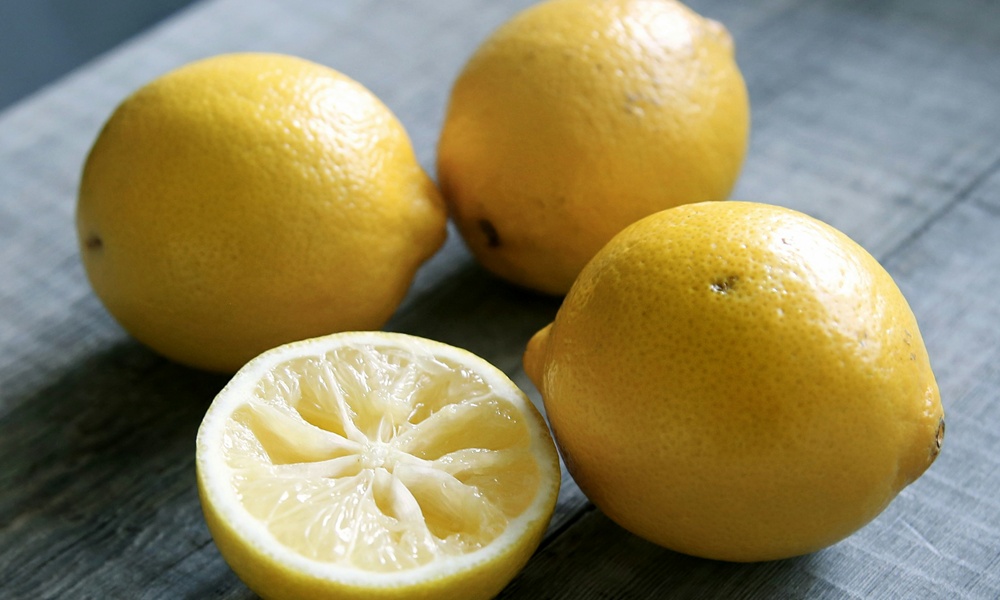 3 limoni interi e una metà giacciono su un tavolo grigio