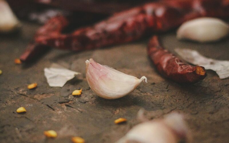 spicchio di aglio pelato intero vicino a dei peperoncini