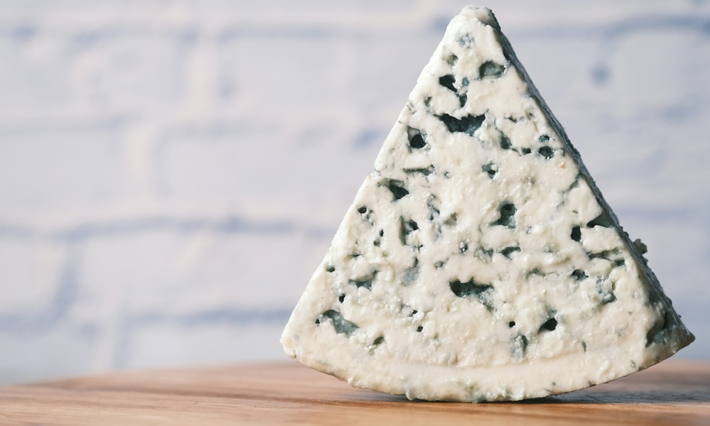 una fetta di gorgonzola su un tagliere in legno