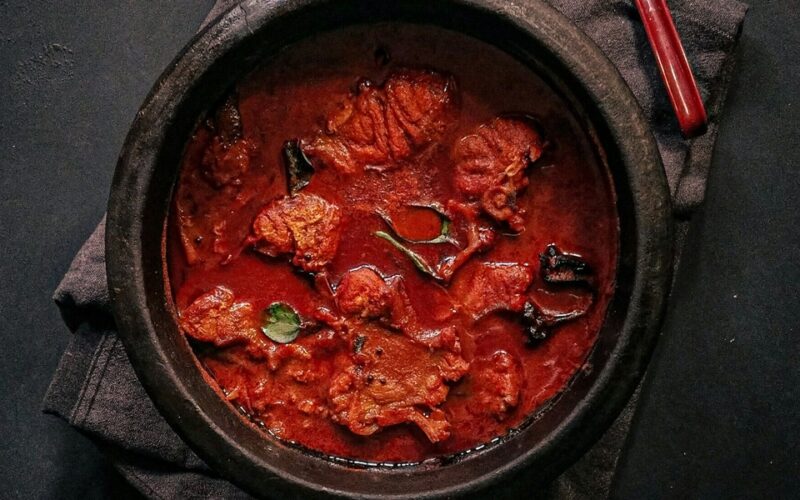 una pentola nera in ghisa che contiene uno spezzatino o un gulasch a base di carne