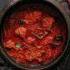 una pentola nera in ghisa che contiene uno spezzatino o un gulasch a base di carne