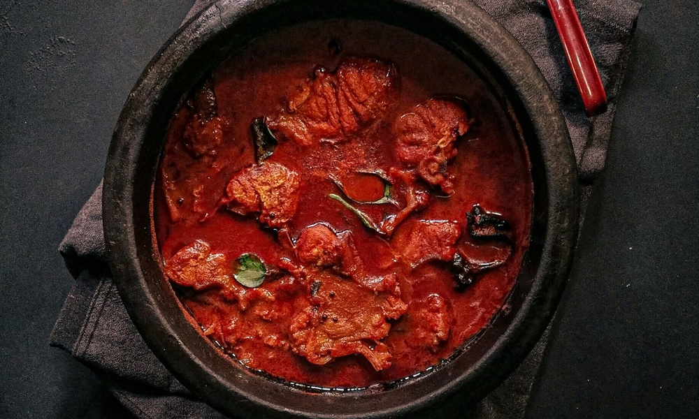 una pentola nera in ghisa che contiene uno spezzatino o un gulasch a base di carne