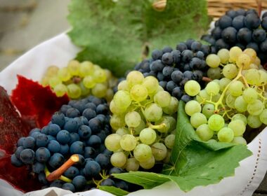 un cesto pieno di grappoli di uva da tavola di colore bianco e rosso/nero