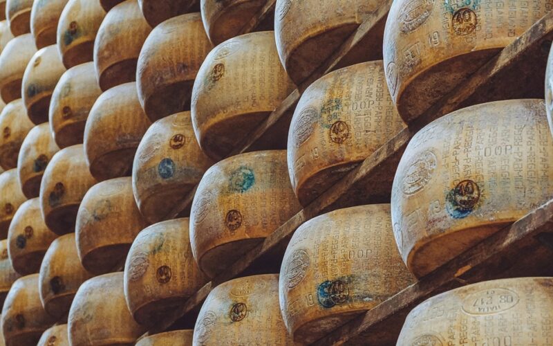 una fila di forme di parmigiano reggiano impilate nelle stanze in cui si fa la stagionatura