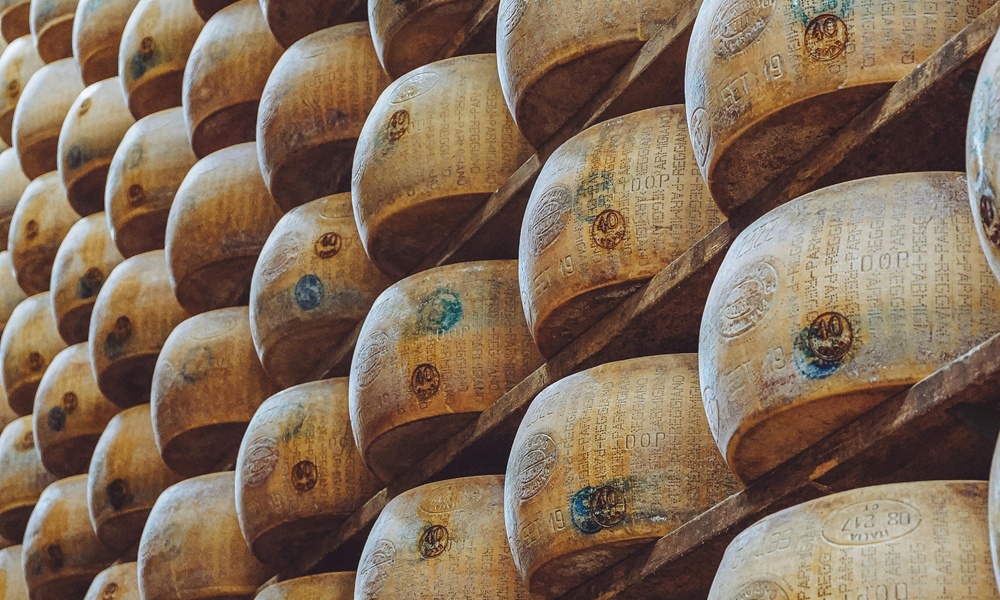 una fila di forme di parmigiano reggiano impilate nelle stanze in cui si fa la stagionatura