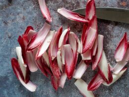 un radicchio spogliato di tutte le sue foglie, poggiato su un tavolo da cucina con accanto un coltello