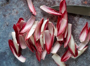 un radicchio spogliato di tutte le sue foglie, poggiato su un tavolo da cucina con accanto un coltello
