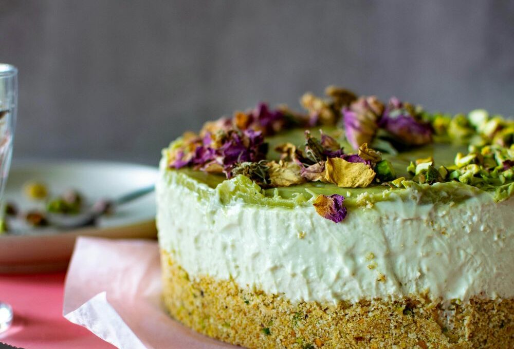 un close up di una cheesecake guarnita con crema al pistacchio e pistacchi tostati
