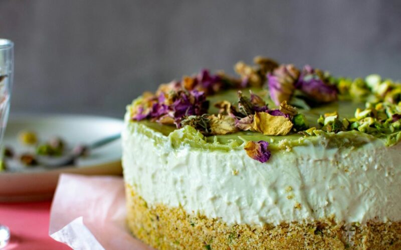 un close up di una cheesecake guarnita con crema al pistacchio e pistacchi tostati