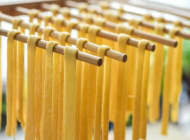 delle aste di legno su cui è poggiata pasta fresca lunga fatta a mano