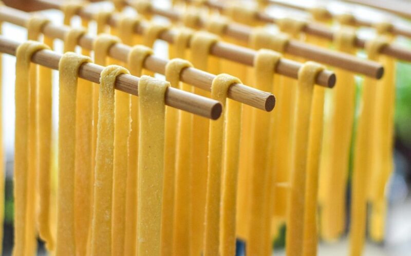 delle aste di legno su cui è poggiata pasta fresca lunga fatta a mano