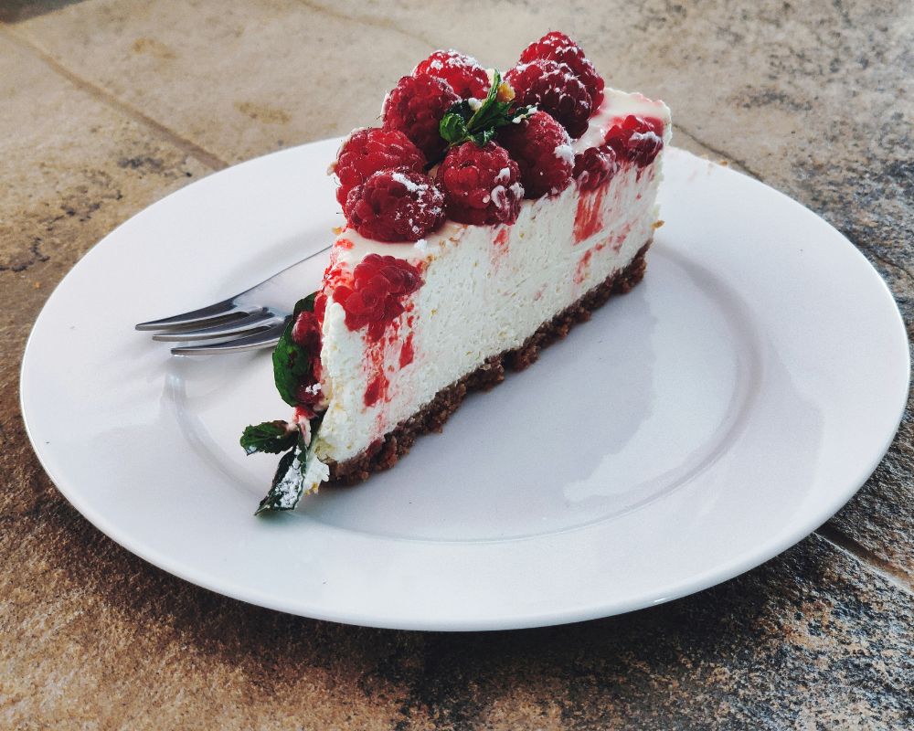 una fetta di cheesecake servita su un piatto da dolci bianco