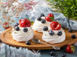 un tagliere in legno su cui sono adagiate tre mini pavlove