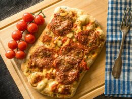 un tagliere con una pinsa condita con dei pomodorini