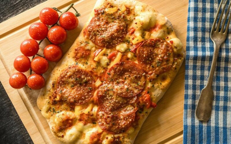 un tagliere con una pinsa condita con dei pomodorini