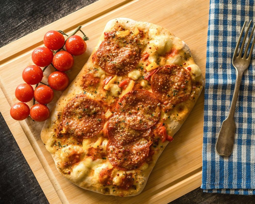 un tagliere con una pinsa condita con dei pomodorini